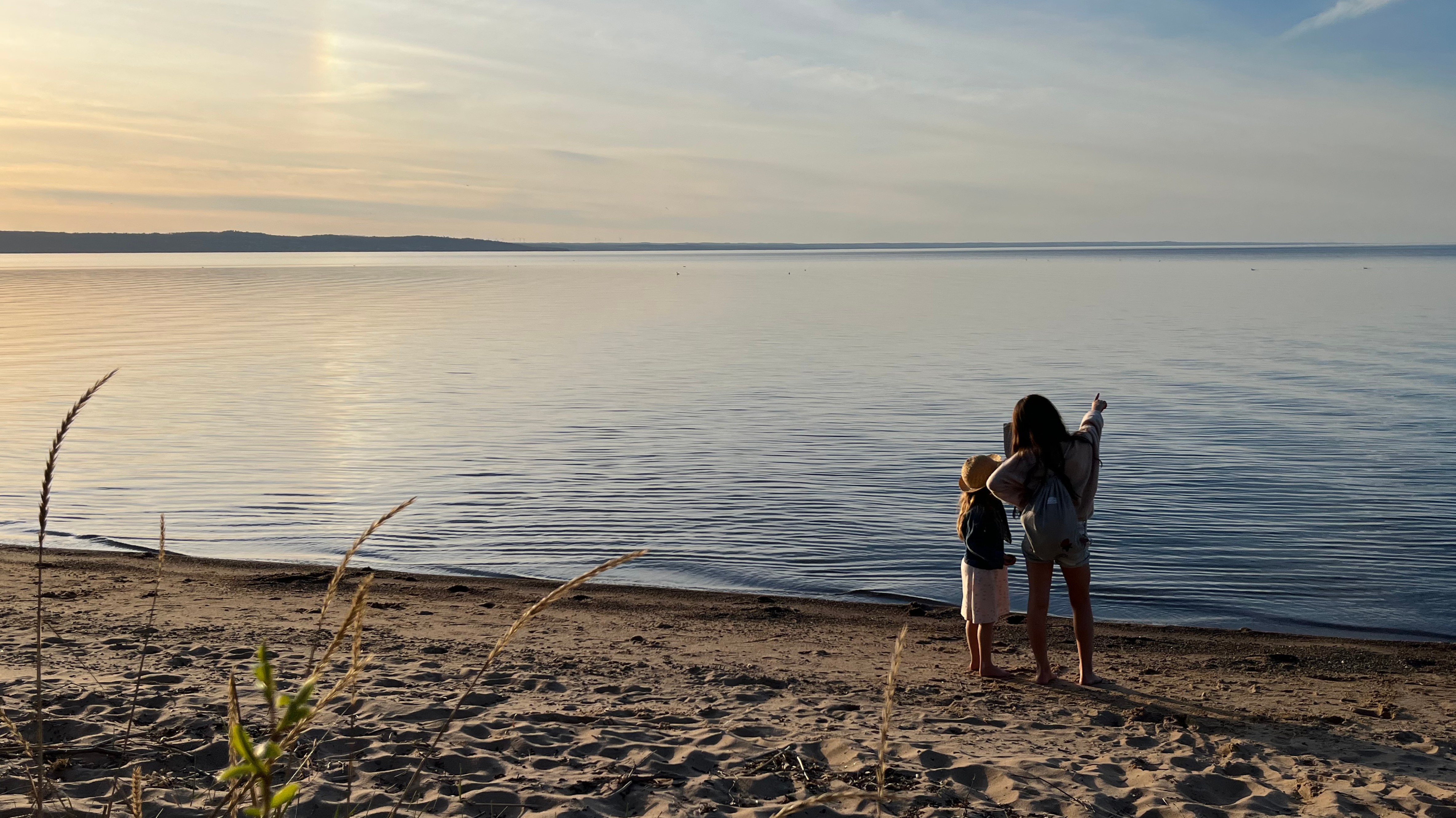Två barn på Vätterns strand kollar ut över vattnet.