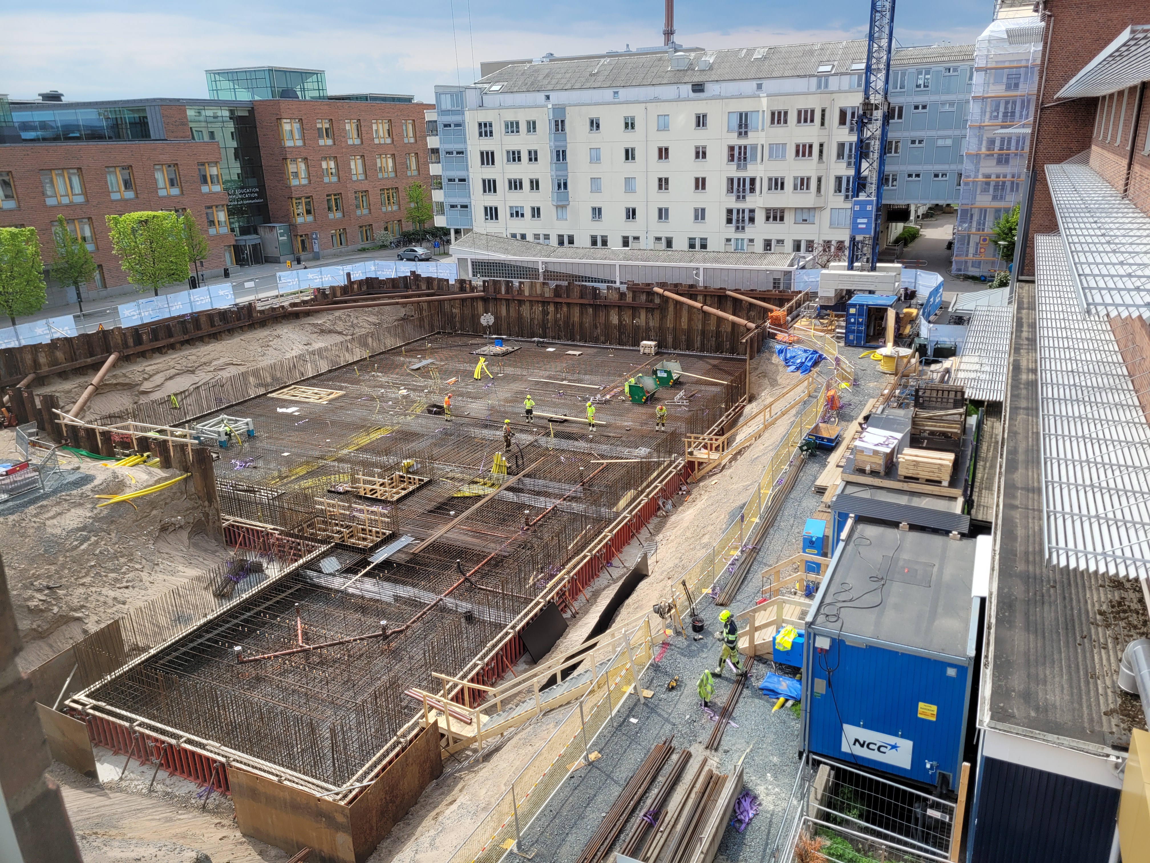 Byggarbetsplatsen sett från nuvarande Science Park House. Byggarbetare slutför det sista armeringsarbetet, med högskolan och Riksbyggens bostäder i bakgrunden.
